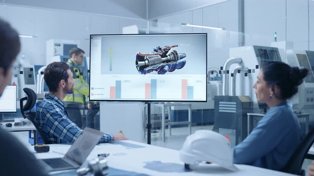 Modern Factory Office Meeting Room: Diverse Team of Engineers, Managers and Investors Talking at Conference Table, Watching Interactive TV that shows Sustainable and Renewable Green Energy Engine