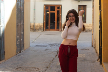 Portrait of rich attractive caucasian young woman with magnifying glass taking a lot of money dollars, in the city, white top and red pants, dark air. Place for your text in copy space.