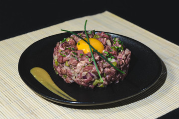 Steak tartar with egg on black plate