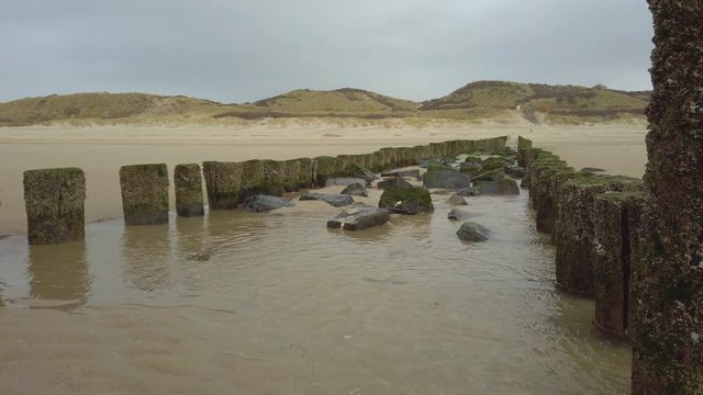 Wavebreakers in front of dunes at the beach in Zoutelande, Netherlands