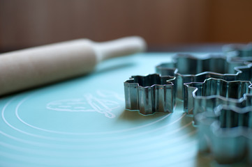 cookie cutters and a rolling pin for dough are on a silicone mat