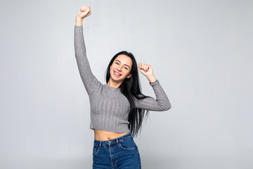 Portrait of a happy young woman dancing on gray background