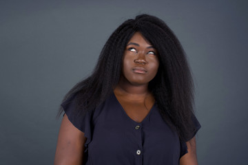 Gloomy, wondering young  African American woman face looking up lips together, being upset thinking...