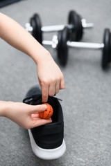 Hand about to drop a shoe freshener ball into athlete footwear with dumbells. Concept for avoiding...