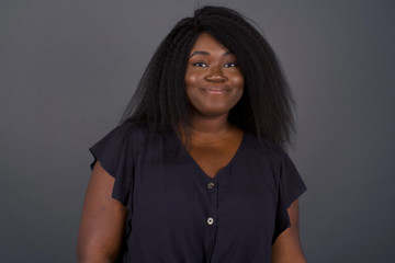 Close up studio shot of beautiful young mixed race woman model with curly dark hair looking at camera with charming cute smile while posing against white blank copy space wall for your content