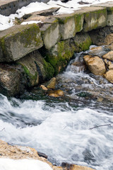 creek runs over stones in early spring