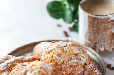 Cup of black coffee with foam and croissants on a light concrete background. Breakfast concept.