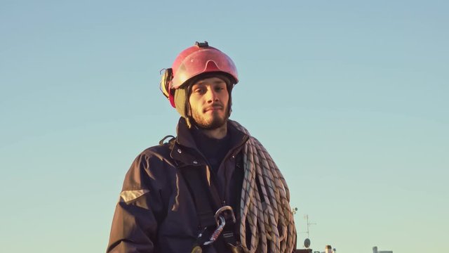 Rope access engineer abseiler with safety harness looks at camera
