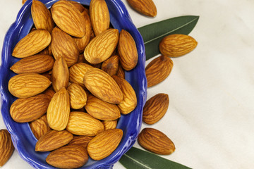 Almond nuts in a blue glass basket and on a white background