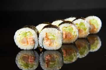 Traditional sushi roll with salmon, cream cheese, shrimp and cucumber on black stone. Japanese food