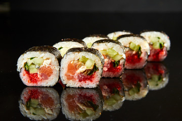 Traditional sushi roll with salmon, cream cheese, caviar and cucumber on black stone. Japanese food