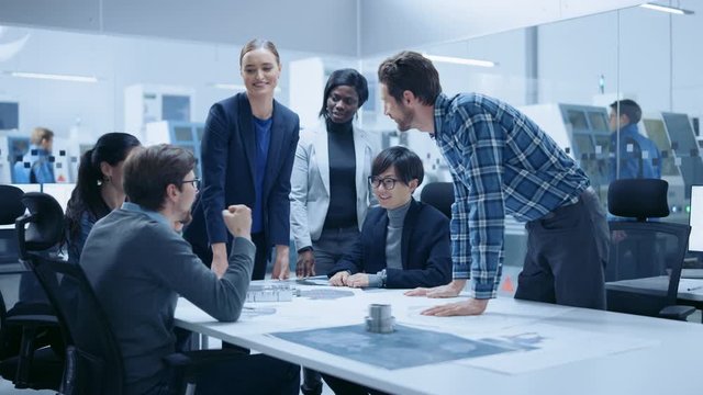 Multi Ethnic Team of Industrial Engineers Standing at the Conference Table Successfully Solve Project Problems, They're Happy and Celebrate with High Five and Cheers. Modern Factory. Slow Motion