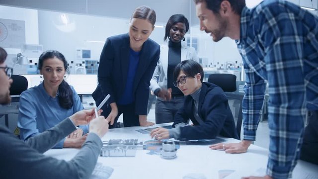 Busy Diverse Team of Engineers and Specialists Gather Around Conference Table, They Discuss Project Drafts and Blueprints, Find Problem Solutions. Industrial Technology Factory / Office Meeting Room