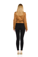 Fototapeta premium Rear View Of Young Woman In Brown Suede Jacket, Black Jeans And High Heels