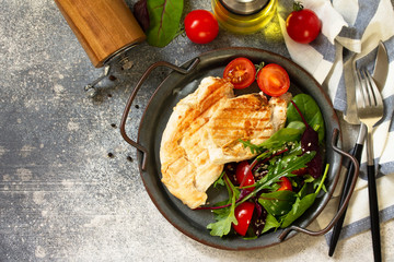 Healthy diet summer lunch. Grilled chicken fillet with vegetable salad on a gray stone countertop. Top view flat lay background. Copy space.