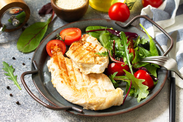 Healthy diet summer lunch. Grilled chicken fillet with vegetable salad on a gray stone countertop.