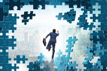 Businessman breaking the wall of jigsaw puzzle