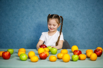 Fototapeta premium Little girl in white T-shirt plays and poses with fruit