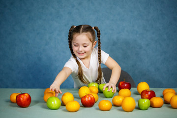 Fototapeta na wymiar Little girl in white T-shirt plays and poses with fruit