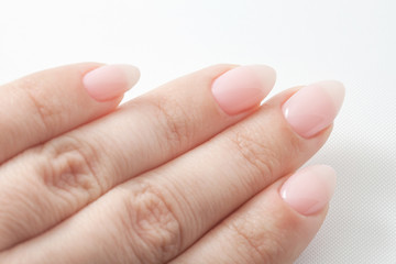 Women's hands with perfect Nude manicure. Nail Polish is a natural pale pink shade.