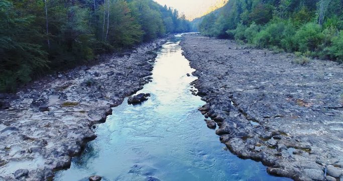 Slow motion aerial flying over Kolpa river, a natural border dividing Croatia and Slovenia. Dolly in
