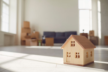 Model of the wooden house on the floor in the new bright sunny house.