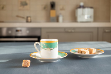 A beautiful coffee cup stands on a dark gray surface on a blurry background of the kitchen interior