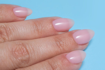 Women's hands with perfect Nude manicure. Nail Polish is a natural pale pink shade.