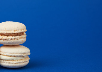 Fototapeta na wymiar stack of white round baked almond flour cakes macarons on a dark blue background