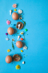 Easter pattern of Eggs with flowers, nests and candies on the blue background. Easter concept. Healthy feeding concept. 