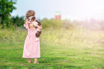 back view little girl hugs puppy tightly chinese crested dog on a pink dress in green background