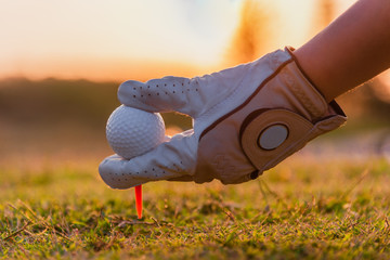 Close up of golfer hand holding golf ball and golf tee