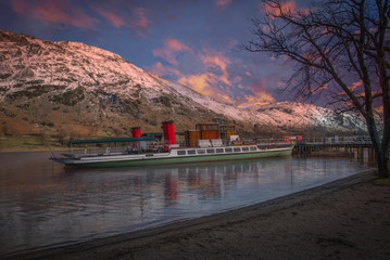 Snow Capped Mountains  Cumbrea & Small Red Funnelled Boat at sunset end of the day.