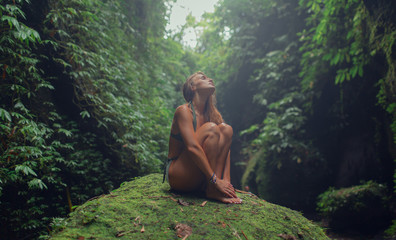 Fototapeta na wymiar Sexy young girl in a green swimsuit in a tropical jungle. Bali.