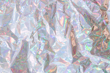 Crumpled holographic wrapping paper with shiny effect. Close up, top view.