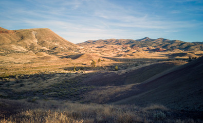 Incredible gold and red hills of clay fossil beds in a semi desert mountain valley on a sunny day of the painted cove trail at the john day fossil beds in Oregon