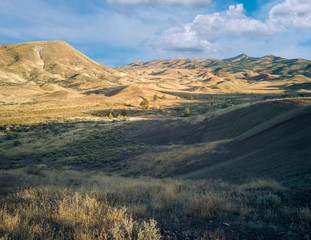 Incredible gold and red hills of clay fossil beds in a semi desert mountain valley on a sunny day of the painted cove trail at the john day fossil beds in Oregon
