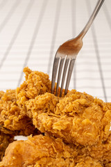 Close Up Hand and Fork on Fried Chickens on white Plate Isolated on table. Look Yummy and Yellow Gold Color.