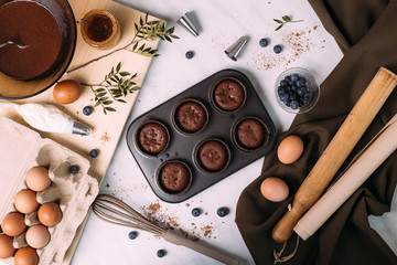 cupcakes with cream and blueberries on kitchen table