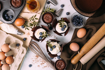 cupcakes with cream and blueberries on kitchen table