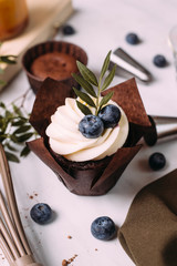 cupcakes with cream and blueberries on kitchen table