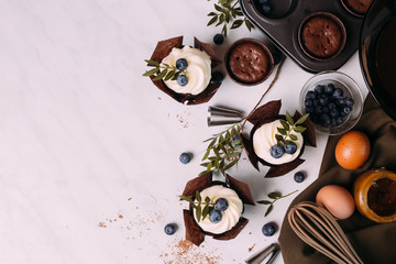 cupcakes with cream and blueberries on kitchen table