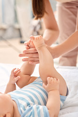 Young adult woman making gentle massage to her little new born baby