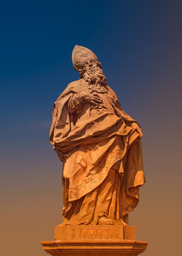 Ancient statue of Saint Fridericus at old city bridge illuminated with golden sun at sunset in Wurzburg, Germany, summer, details, closeup