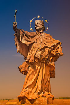 Ancient statue of Saint Nepomuk at old city bridge illuminated with golden sun at sunset in Wurzburg, Germany, summer, details