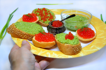  plate with sandwiches in hand with caviar and guacamole