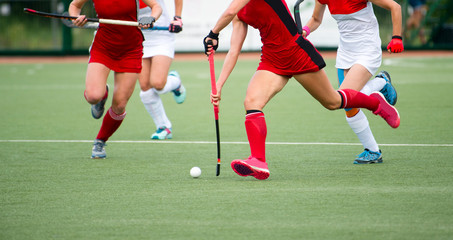 Field hockey players challenge eachother for possession of the ball on the midfield battle of a...