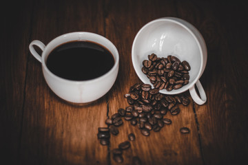 cup of coffee with beans on wooden table