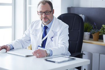 Portrait of senior doctor in office sitting at the desk