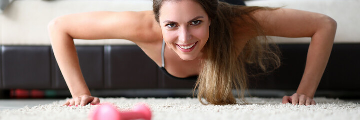 Portrait of perfect smiling sportswoman pumping up at home. Wonderful woman with perfect figure...